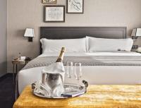 a bed with a bottle of champagne and glasses on a table at The Principal Madrid, Small Luxury Hotels in Madrid