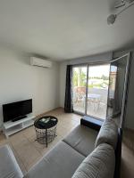 ein Wohnzimmer mit einem Sofa und einem TV in der Unterkunft Appartement moderne en résidence avec piscine in Mèze