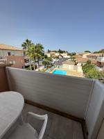 einen Balkon mit einem Tisch und Poolblick in der Unterkunft Appartement moderne en résidence avec piscine in Mèze