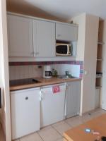 a kitchen with white cabinets and a microwave at chez josette 300m de l ocean in Soulac-sur-Mer