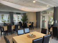 una sala da pranzo con tavoli, sedie e finestre di Airport Szálló a Tököl