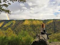 a woman sitting on a rock watching a rainbow at Gîte du Busatier in Marcillac-la-Croisille