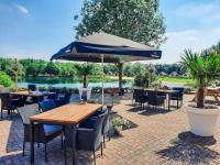 eine Terrasse mit Tischen und Stühlen und einem Sonnenschirm in der Unterkunft Gezellige vakantiewoning aan het water in Ewijk - recreational only no workers in Ewijk