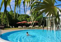 a man swimming in a pool with palm trees at Heide Spa Hotel &amp; Resort in Bad Düben