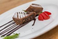 a piece of chocolate cake and strawberries on a plate at Hotel Riviera in Melide