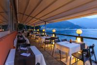 a restaurant with tables and chairs and a view of the water at Hotel Riviera in Melide