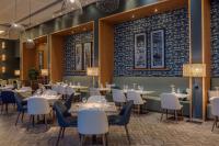 a dining room with tables and chairs and a wall with blue tiles at Hilton Evian Les Bains in Évian-les-Bains