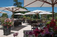 a patio with tables and chairs with umbrellas and flowers at Hilton Evian Les Bains in Évian-les-Bains