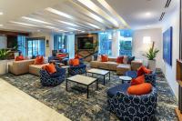Una sala de estar con sofás, mesas y ventanas. en Hilton Garden Inn West Palm Beach I95 Outlets, en West Palm Beach