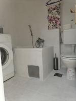 a bathroom with a toilet and a washing machine at Flowers Apartment Tuzla in Tuzla