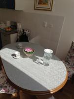a table with a bowl of flowers and a glass at Flowers Apartment Tuzla in Tuzla