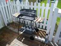 a grill sitting on a deck next to a white fence at Chez Laurent et Sandrine in Chantraine