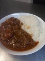 a plate of food with meat and rice on a table at The Border Post, Bed and Breakfast in Bergville