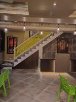 Una escalera en un vestíbulo con sillas verdes. en Hotel Garuda Executive Latur, en Lātūr