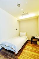 a bedroom with a large white bed and a table at Single inn- KAOHSIUNG LINSEN in Kaohsiung