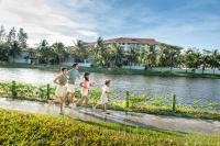a family walking along the water in front of a lake at Vinpearl Resort & Spa Phu Quoc in Phú Quốc