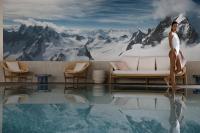 a woman sitting on the edge of a pool with a mountain at Hôtel Royal in Évian-les-Bains