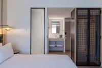 a bedroom with a white bed and a bathroom at Hilton Garden Inn Marseille Provence Airport in Marignane