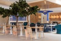 a restaurant with tables and chairs and trees at Hilton Garden Inn Marseille Provence Airport in Marignane