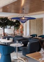 a restaurant with blue chairs and tables and a chandelier at Hilton Garden Inn Marseille Provence Airport in Marignane
