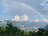 a rainbow in the sky over a city at La coccinelle in Noyarey