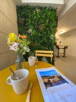 a table with a book and cups and flowers on it at Cosy Green - WIFI HD - NETFLIX GRATUIT in Avignon