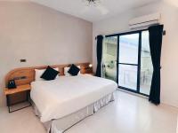 a bedroom with a bed and a large window at Qixingtan Xinghai B&amp;B in Dahan