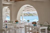 Un restaurante con mesas y sillas blancas y vista al mar. en Nammos Hotel Mykonos, en Psarou