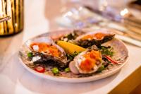 a plate of food with oysters and vegetables on a table at Ruim comfortabel appartement centrum Breda MET restaurant! in Breda