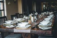 una larga mesa de madera con platos y copas de vino en Umbono Private Game Lodge, en Alexandria