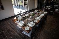 Una larga mesa de madera en un restaurante con sillas y platos. en Umbono Private Game Lodge, en Alexandria