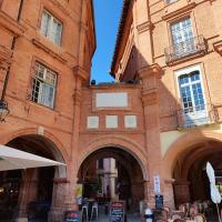 a brick building with arches and tables and chairs at Numéro 6 - Place Nationale - Wifi et Fibre in Montauban