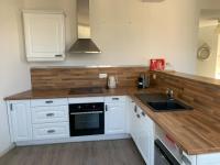 a kitchen with white cabinets and a wooden counter top at La cabine d&#39;Amélie in Veules-les-Roses