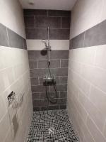 a bathroom with a shower with gray tiles at Gîte entre mer et montagne in Saint-Vincent