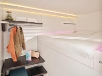 a white bedroom with a bed and a shelf at CityHub Amsterdam in Amsterdam