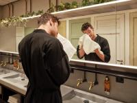 a man standing in front of a bathroom mirror wiping his face at CityHub Amsterdam in Amsterdam