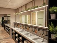 a row of sinks in a bathroom with plants at CityHub Amsterdam in Amsterdam