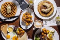 a table topped with plates of food and waffles at Roxy Hotel New York in New York