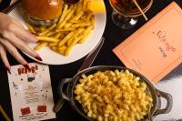 a table with a plate of macaroni and cheese and french fries at Roxy Hotel New York in New York