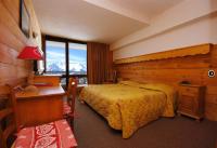 a bedroom with a bed and a desk and a window at Hôtel Le Dôme in L&#39;Alpe-d&#39;Huez