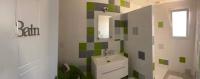 a bathroom with a sink and a green and white tile wall at Chambre les Hortensias in Challans