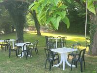 eine Gruppe von Tischen und Stühlen in einem Park in der Unterkunft L'Oasienne in Lissac et Mouret