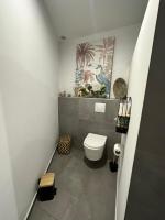 a bathroom with a toilet and a painting on the wall at La Parenthèse chez Seb et Gwen in Le Tampon