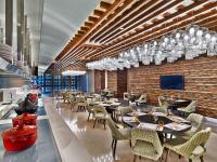 Un restaurante con mesas y sillas en una sala. en V Hotel Dubai, Curio Collection by Hilton, en Dubái