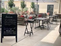 Un restaurante con mesas y sillas y un cartel. en Mercure Avignon TGV Hotel & Spa, en Aviñón