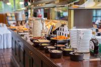a buffet line with bowls of food and plates at Trans World Hotel Donauwelle in Linz