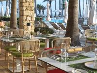 Un restaurante con mesas y sillas y una piscina. en Leonardo Plaza Cypria Maris Beach Hotel & Spa, en Pafos