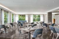 uma sala de jantar com mesas, cadeiras e janelas em TRYP by Wyndham Corfu Dassia em Dassia