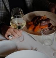 a person holding a glass of wine next to a plate of food at PALAZZO DE' ROSSI HOTEL in Sasso Marconi