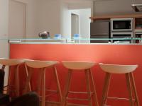 a kitchen with a red counter with stools in it at L’Arabesque, villa de charme avec piscine in Arradon